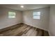 A bright bedroom with hardwood floors and freshly painted white walls with two windows at 1851 S Clearview Dr, Henderson, NC 27536