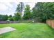 Grassy backyard featuring mature trees, a privacy fence, and a patio area at 201 Masterwood Way, Morrisville, NC 27560