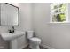 Powder room features a pedestal sink, modern faucet, a large mirror, and a window at 2101 Wimberly Woods Dr, Sanford, NC 27330