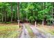 Long gravel driveway leading through a lush, green forest towards the property at 224 Oakcrest Dr, Wake Forest, NC 27587