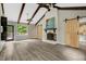 Bright living room boasts ceiling beams, a brick fireplace, barn doors, and deck access with wooded views at 224 Oakcrest Dr, Wake Forest, NC 27587