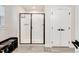 Modern bathroom featuring a glass-enclosed shower, sleek tile floors, and a dark storage bench at 232 Randleman Ct, Holly Springs, NC 27540