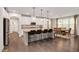 Open-concept kitchen with white cabinets, granite countertops, a kitchen island with bar stools, and stainless steel appliances at 232 Randleman Ct, Holly Springs, NC 27540