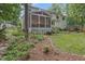 Landscaped backyard featuring a screened-in porch, mature trees, and garden at 314 Chanticlair Dr, Apex, NC 27502