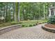 Beautiful backyard featuring a brick patio, lush lawn, colorful hydrangeas, and mature trees at 314 Chanticlair Dr, Apex, NC 27502