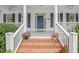 Cozy front porch featuring brick steps, white railings, decorative plants, and a welcoming blue front door at 314 Chanticlair Dr, Apex, NC 27502