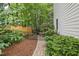 Lush backyard featuring manicured garden beds, mature trees, and a wrought iron gate at 314 Chanticlair Dr, Apex, NC 27502