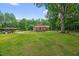 Expansive backyard featuring a large lawn, mature trees and a covered parking area at 3315 Mebane Oaks Rd, Mebane, NC 27302