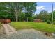 Expansive backyard featuring a large lawn, mature trees, a wooden deck, and a charming shed at 3315 Mebane Oaks Rd, Mebane, NC 27302