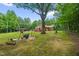 Mature trees shade an expansive backyard with outdoor seating and play equipment at 3315 Mebane Oaks Rd, Mebane, NC 27302