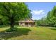 A picturesque front exterior view with a brick facade, a quaint front porch, and a lush, sprawling green lawn at 3315 Mebane Oaks Rd, Mebane, NC 27302