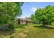 A serene view of a charming home with a covered porch, surrounded by lush greenery and mature trees at 3315 Mebane Oaks Rd, Mebane, NC 27302