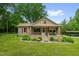 Charming brick home featuring a cozy front porch, landscaped garden, and a covered carport in the background at 3315 Mebane Oaks Rd, Mebane, NC 27302