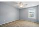 This bedroom features carpeted floors, a ceiling fan, and a window at 409 Kilcornac Ct, Fuquay Varina, NC 27526