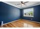 Serene bedroom featuring hardwood floors, a ceiling fan, and a large window with bright, natural light at 409 Kilcornac Ct, Fuquay Varina, NC 27526
