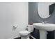 Modern half bathroom with a pedestal sink, round mirror, and clean, contemporary design at 409 Kilcornac Ct, Fuquay Varina, NC 27526