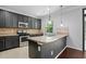 Well-lit kitchen with stainless steel appliances, dark cabinets, a breakfast bar and tile backsplash at 409 Kilcornac Ct, Fuquay Varina, NC 27526