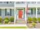 Inviting front entrance with a bright red door, classic gray siding, and beautifully landscaped bushes at 470 E Wellesley Dr, Clayton, NC 27520