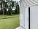 View of a building with white siding and double doors leading to an open, grassy area surrounded by trees at 656 Barneswyck Dr, Fuquay Varina, NC 27526