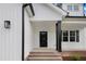 Close-up of a home's front door with black door and pillars, white siding, and brick stairs at 80 Birchtop Cir, Zebulon, NC 27597