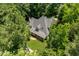 An aerial view of a beautiful home with a complex roofline surrounded by lush, mature trees at 100 Donald Dr, Pittsboro, NC 27312