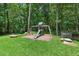 Backyard playground set with swings and a slide in a lush, wooded area at 100 Donald Dr, Pittsboro, NC 27312