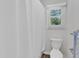 Well-lit bathroom featuring a toilet, shower with white curtain, and window at 100 Windvale Ct, Cary, NC 27518