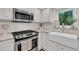 Close-up of kitchen featuring stainless steel appliances, white subway tile backsplash, and a farmhouse sink at 100 Windvale Ct, Cary, NC 27518