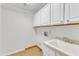 Utility room with sink, cabinets, and connections for a washer and dryer at 100 Windvale Ct, Cary, NC 27518