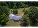 Sprawling ranch-style home with a gray roof surrounded by lush greenery and a spacious yard at 1067 Thompson Rd, Four Oaks, NC 27524