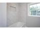 Bathroom bathtub with marble tile surround and a shower niche for storage at 1067 Thompson Rd, Four Oaks, NC 27524
