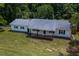 Single story home with white brick, gray roof, black shutters, and covered porch surrounded by lawn at 1067 Thompson Rd, Four Oaks, NC 27524