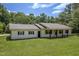 Charming ranch style home with white exterior, black shutters, gray roof and a spacious front yard at 1067 Thompson Rd, Four Oaks, NC 27524