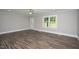 Bright living room with wood-look floors, ceiling fan, gray walls, and large windows at 1067 Thompson Rd, Four Oaks, NC 27524
