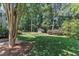 Expansive backyard with mature trees and a charming playhouse nestled in the landscape at 115 E Seve Ct, Morrisville, NC 27560