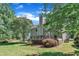 A view of the house from the backyard featuring mature trees, a spacious lawn, and a deck at 115 E Seve Ct, Morrisville, NC 27560
