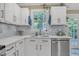 Well-lit kitchen featuring white cabinetry, quartz countertops, stainless steel appliances, and a charming window view at 115 E Seve Ct, Morrisville, NC 27560