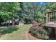 A charming playhouse is nestled among mature trees in the expansive backyard at 115 E Seve Ct, Morrisville, NC 27560