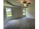Spacious bedroom featuring a tray ceiling with a ceiling fan and large windows at 140 Oakfield Trace Dr, Four Oaks, NC 27524