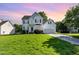 Charming two-story home with manicured lawn, attached garage, and inviting curb appeal under a lovely sunset at 1613 Patterson Grove Rd, Apex, NC 27502