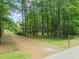 View of the home down the gravel driveway, surrounded by mature trees at 20 Timberlyne Rd, Chapel Hill, NC 27514