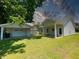 Exterior view of the backyard showcasing the home and detached garage with lush greenery and blue skies at 202 S Pearl St, Princeton, NC 27569