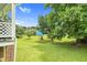 Expansive backyard with mature trees, landscaped garden and blue house in the distance at 209 Bradley Dr, Benson, NC 27504