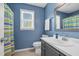 Bright blue bathroom featuring a white vanity, framed mirror, and a colorful striped shower curtain at 209 Bradley Dr, Benson, NC 27504