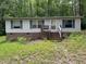 Single story home with brick foundation, light siding, blue shutters, and a small porch nestled in a wooded area at 3539 Charlies Ct, Wake Forest, NC 27587
