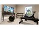 Home gym featuring an exercise bike, weight rack, mounted television, and a bright window for an invigorating workout space at 426 Rowe Way, Knightdale, NC 27545