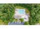 Birds eye view of a large community pool, splash pad, clubhouse, lounge chairs, and wooded perimeter at 7336 Capulin Crest Dr, Apex, NC 27539