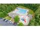 Full aerial view of the resort style pool featuring a splash pad, pool, lounge chairs, clubhouse, and parking at 7336 Capulin Crest Dr, Apex, NC 27539