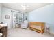 Well-lit Bedroom with a wooden crib, glider, and a book stand near a window with view to the outside at 7336 Capulin Crest Dr, Apex, NC 27539