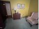 A bedroom featuring a green carpet, a lamp atop a three-drawer dresser, and a pink armchair at 10 Winchester Ct, Durham, NC 27707